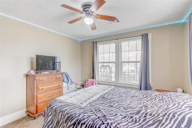 bedroom with visible vents, light carpet, a textured ceiling, baseboards, and ceiling fan