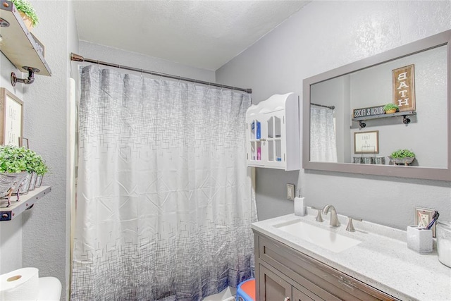 full bath with vanity, a shower with shower curtain, toilet, and a textured wall