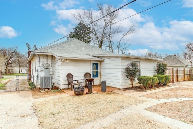 view of front of house with a gate, a fire pit, fence, and central AC