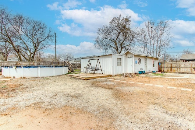 back of property with a deck, a fenced backyard, and a fenced in pool