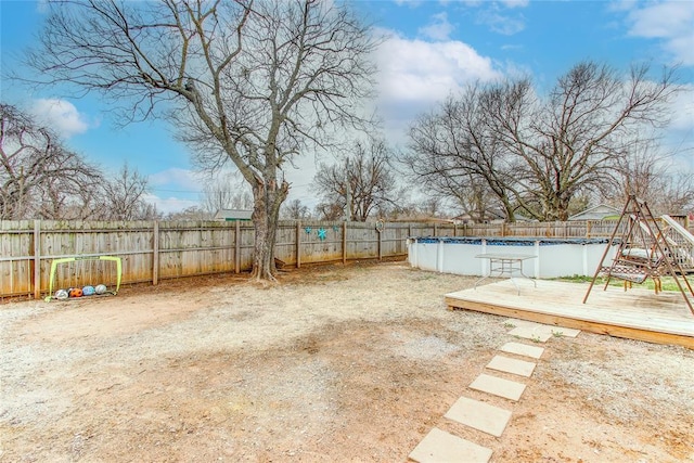 view of yard with a deck, a fenced backyard, and a fenced in pool