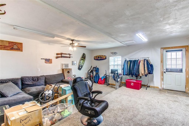 living room featuring a ceiling fan, a textured ceiling, carpet, baseboards, and attic access