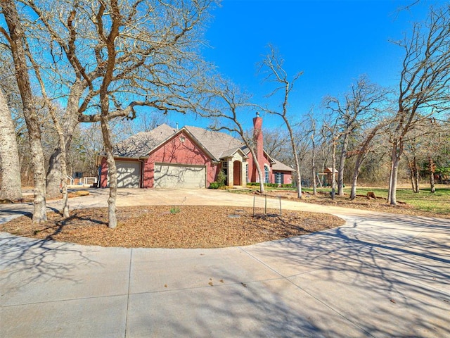 view of front facade featuring a garage, concrete driveway, and a chimney