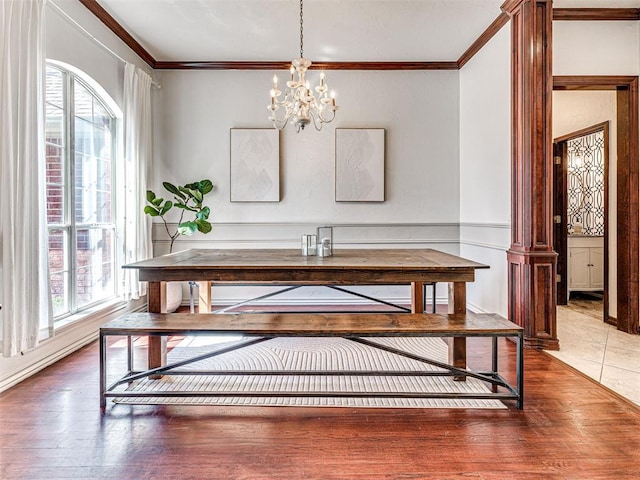 dining room with a notable chandelier, wood finished floors, wainscoting, and ornamental molding