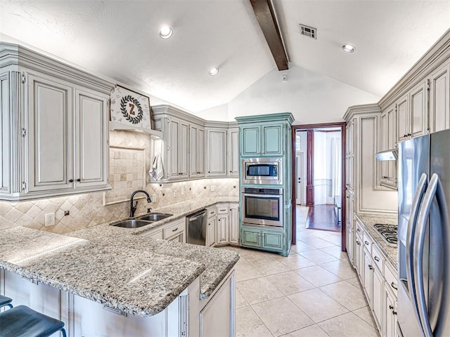 kitchen featuring a peninsula, vaulted ceiling with beams, a sink, decorative backsplash, and appliances with stainless steel finishes