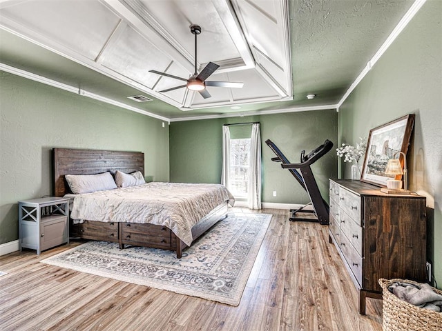 bedroom featuring visible vents, ornamental molding, wood finished floors, baseboards, and a textured wall