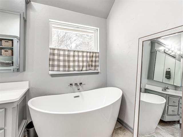 full bathroom with a freestanding bath, vanity, and vaulted ceiling