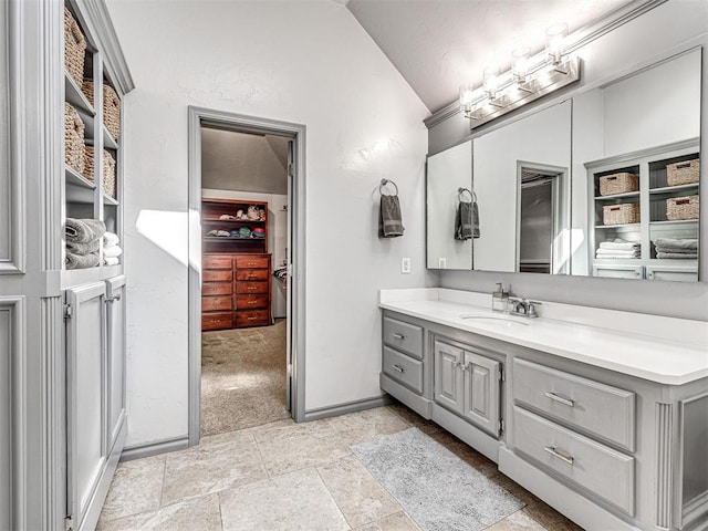 bathroom featuring vanity, vaulted ceiling, and baseboards