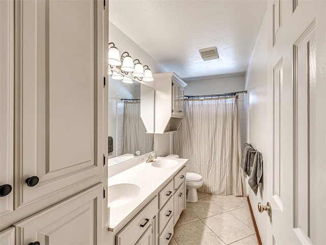 bathroom with a sink, double vanity, toilet, and a textured ceiling