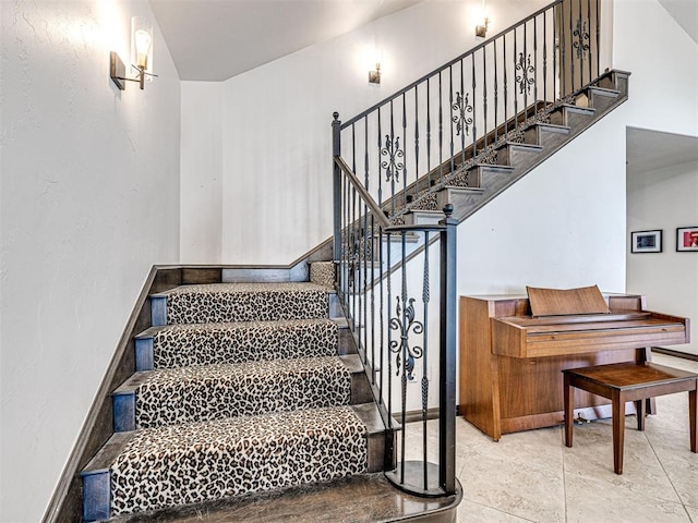 stairway featuring baseboards and a towering ceiling