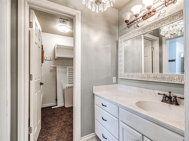 bathroom featuring visible vents, an inviting chandelier, vanity, and baseboards