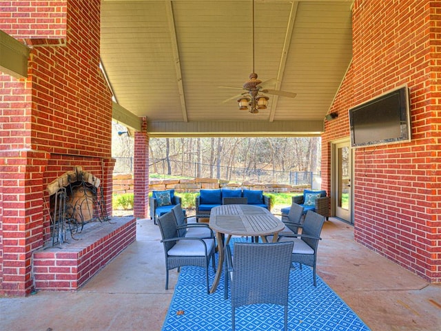 view of patio / terrace with an outdoor living space with a fireplace, fence, and ceiling fan