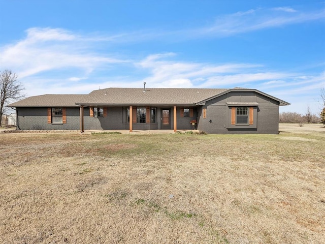 single story home with a front lawn, a patio area, brick siding, and a shingled roof