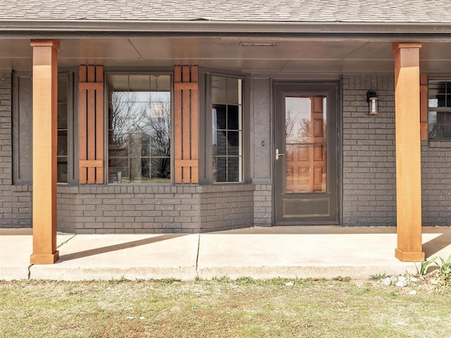 property entrance with brick siding and roof with shingles