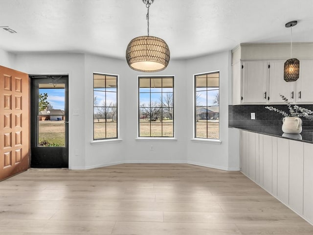 unfurnished dining area featuring visible vents, a healthy amount of sunlight, and light wood-type flooring