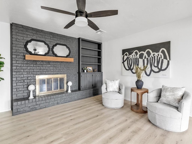 sitting room featuring visible vents, baseboards, ceiling fan, a fireplace, and wood finished floors