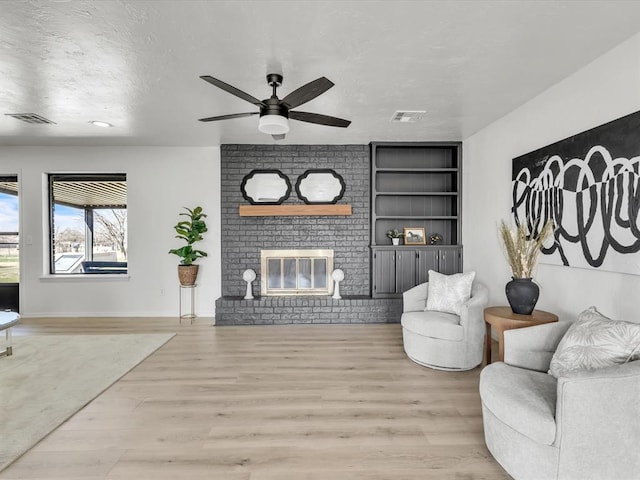 living area featuring visible vents, a textured ceiling, ceiling fan, and wood finished floors