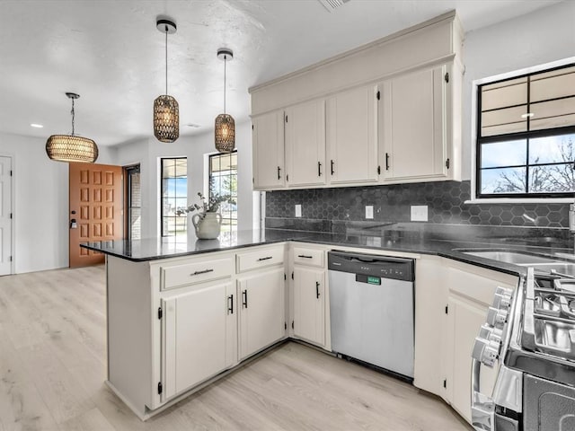 kitchen with a sink, dark countertops, appliances with stainless steel finishes, and a peninsula