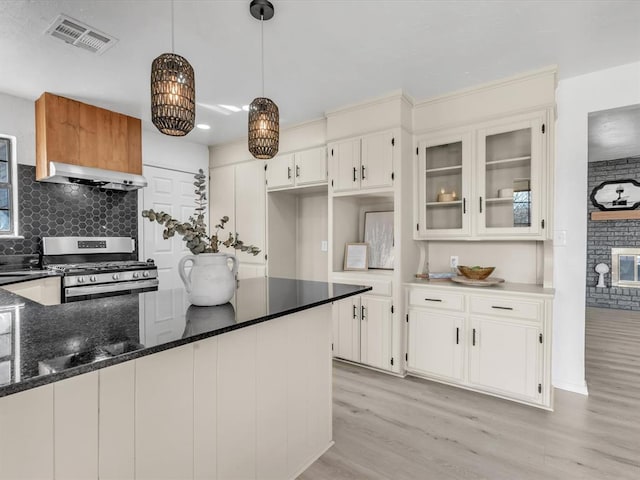 kitchen with visible vents, light wood-type flooring, gas stove, white cabinets, and extractor fan