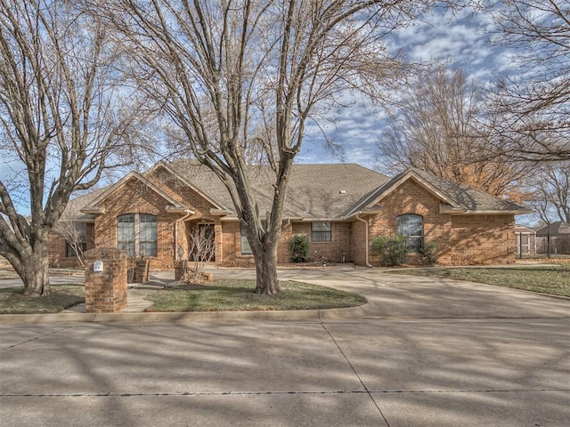 ranch-style home with brick siding, concrete driveway, and a shingled roof