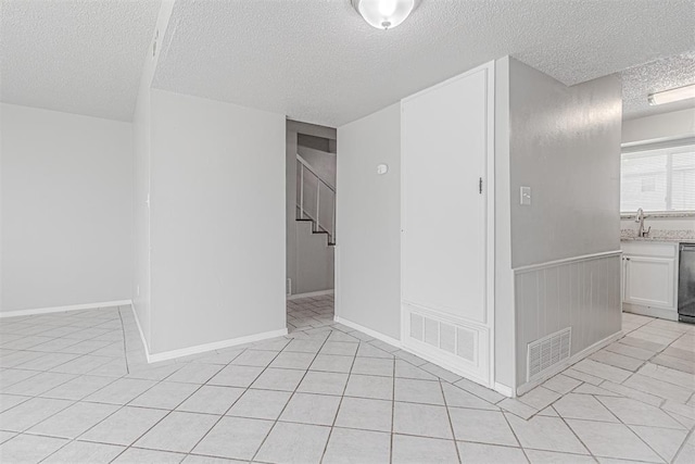 spare room featuring a sink, visible vents, a textured ceiling, and stairway