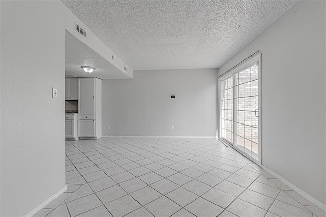 unfurnished living room with light tile patterned flooring, baseboards, visible vents, and a textured ceiling