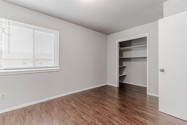 unfurnished bedroom featuring a closet, baseboards, a textured ceiling, and wood finished floors