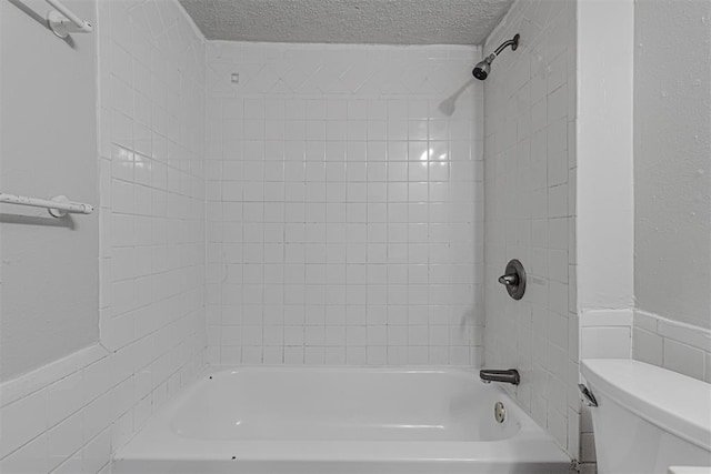 bathroom featuring a wainscoted wall, a textured ceiling, shower / bathtub combination, and toilet