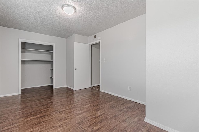 unfurnished bedroom with baseboards, wood finished floors, a closet, and a textured ceiling