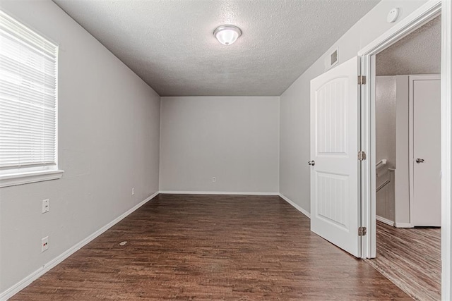 interior space featuring visible vents, baseboards, dark wood-type flooring, and a textured ceiling