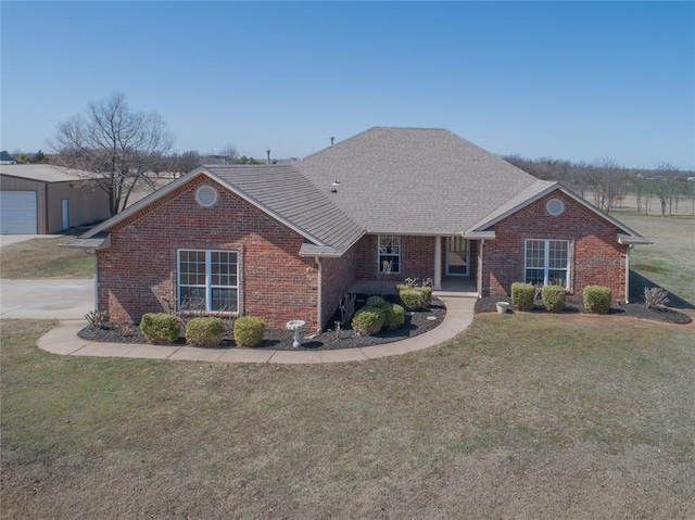 view of front facade featuring a front yard, brick siding, and roof with shingles