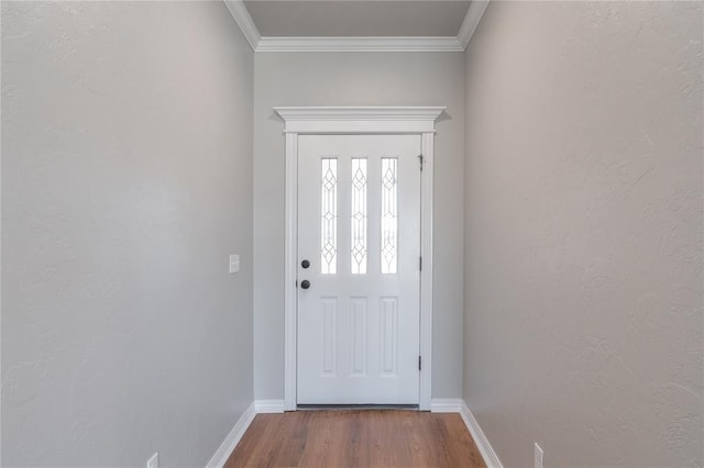 doorway to outside with a textured wall, wood finished floors, baseboards, and ornamental molding