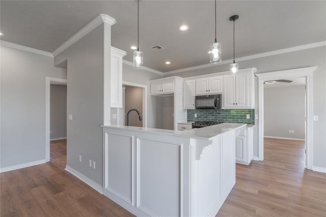 kitchen featuring visible vents, black microwave, light countertops, decorative backsplash, and white cabinets