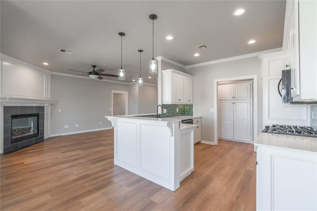 kitchen with visible vents, a peninsula, open floor plan, and a tile fireplace