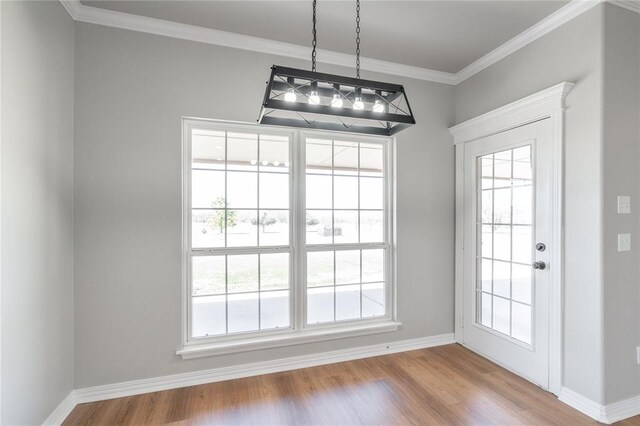 unfurnished dining area with crown molding, wood finished floors, and baseboards