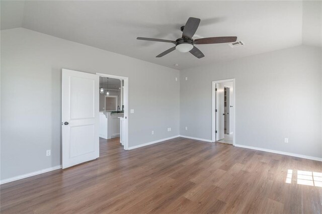 unfurnished room with visible vents, baseboards, lofted ceiling, wood finished floors, and a ceiling fan