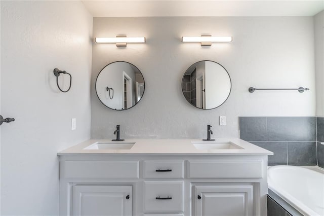 bathroom with double vanity, a bath, and a sink