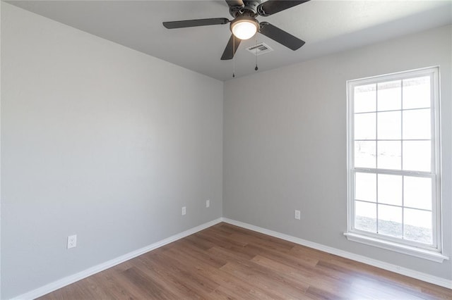 unfurnished room with visible vents, ceiling fan, baseboards, and wood finished floors