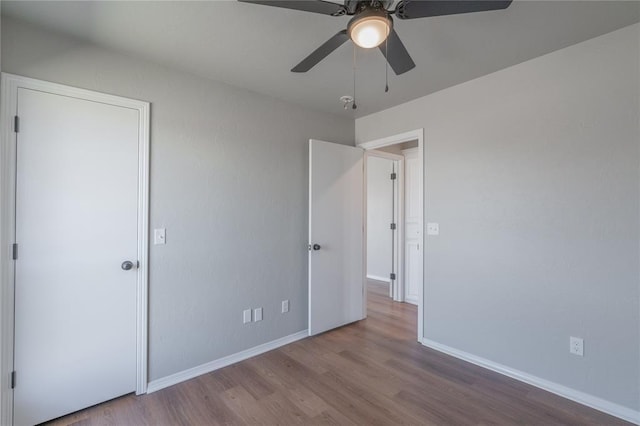 unfurnished bedroom with a ceiling fan, wood finished floors, and baseboards