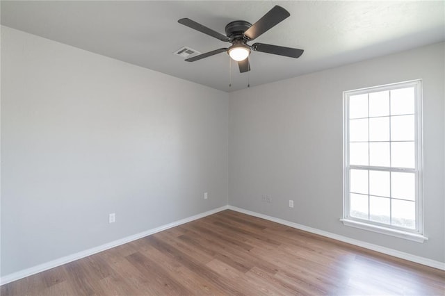 spare room featuring ceiling fan, visible vents, baseboards, and wood finished floors