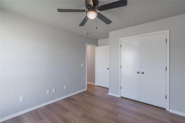 unfurnished bedroom with wood finished floors, baseboards, a closet, and ceiling fan