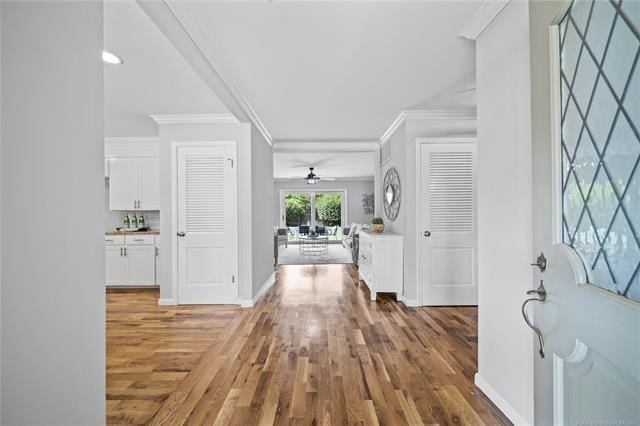 foyer entrance featuring baseboards, light wood finished floors, and ornamental molding