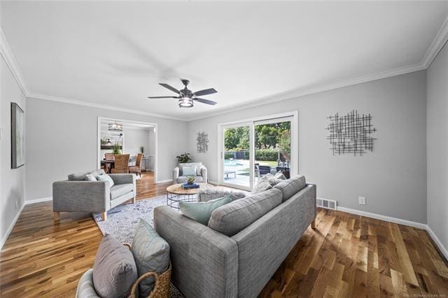 living room featuring visible vents, ornamental molding, a ceiling fan, wood finished floors, and baseboards