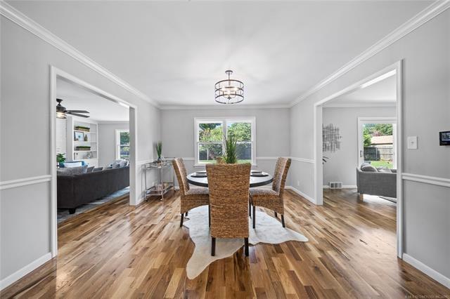 dining area featuring visible vents, a notable chandelier, a healthy amount of sunlight, and wood finished floors