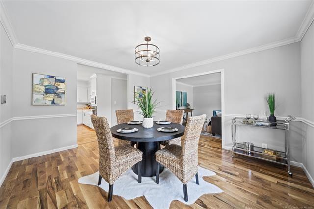 dining space featuring a notable chandelier, baseboards, light wood-type flooring, and ornamental molding