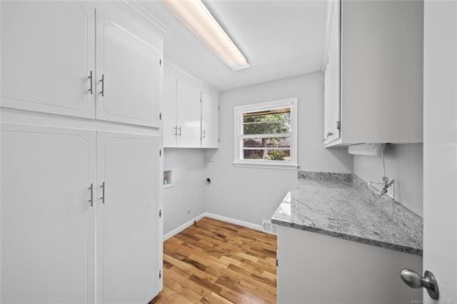 laundry room featuring light wood finished floors, baseboards, hookup for a washing machine, cabinet space, and electric dryer hookup