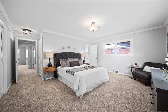 bedroom with visible vents, baseboards, light colored carpet, and crown molding