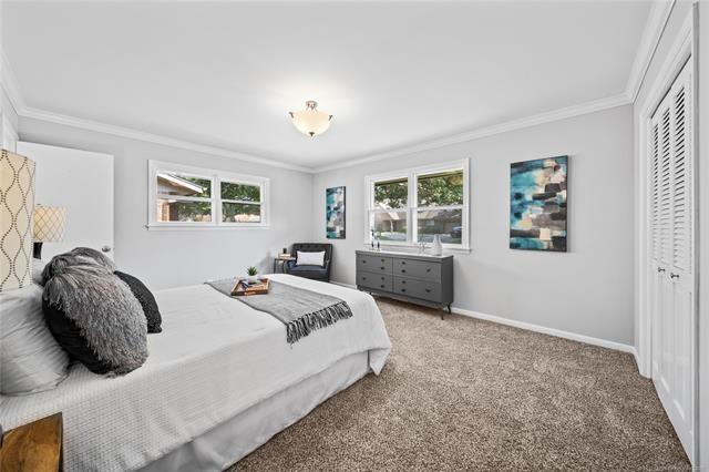 carpeted bedroom featuring a closet, multiple windows, and ornamental molding