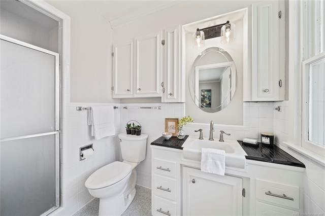 bathroom with toilet, a stall shower, tile walls, wainscoting, and vanity