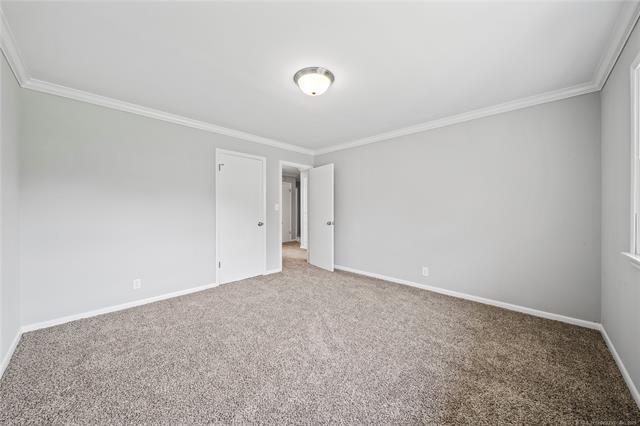 carpeted spare room featuring baseboards and ornamental molding